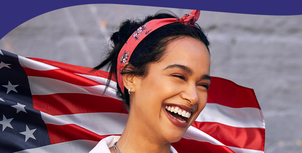 Patriotic woman smiling in front of an American flag